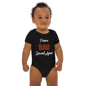 Puede incluir: Un body de bebé negro con texto blanco que dice "Future BAU Special Agent". La palabra "BAU" está en rojo.