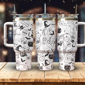 Könnte beinhalten: Drei weiße Edelstahlbecher mit schwarz-weißen Halloween-Designs. Die Becher haben Deckel und Strohhalme. Die Designs beinhalten Geister, Fledermäuse, Kürbisse und andere Halloween-Bilder.