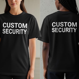 Puede incluir: Camisetas negras con las palabras "CUSTOM SECURITY" impresas en blanco. El texto está centrado en la parte delantera y trasera de las camisetas. Las camisetas tienen mangas cortas y cuello redondo.