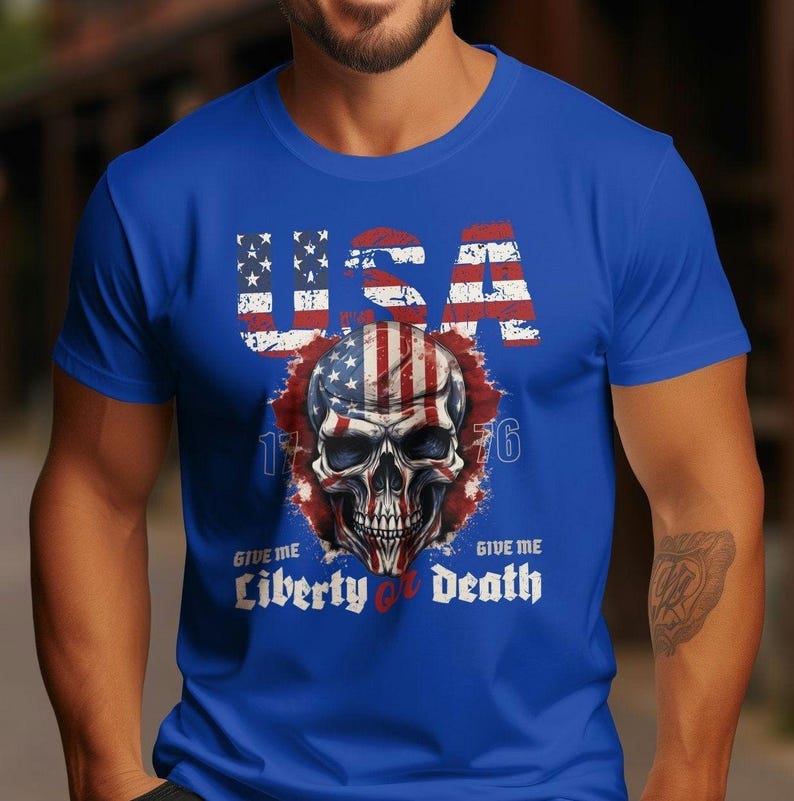 May include: A blue t-shirt featuring a skull graphic. The skull is decorated with the American flag and the text "USA 1776 Give Me Liberty or Death".