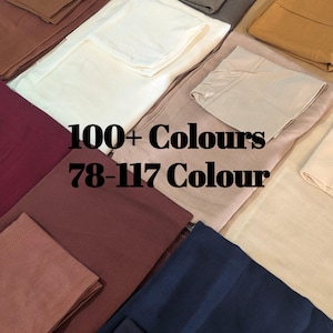 May include: A collection of folded fabric swatches in various solid colors including white, cream, tan, brown, burgundy, and navy blue. The image features the text 100+ Colours 78-117 Colour overlaid in black, showcasing a wide range of textile options.
