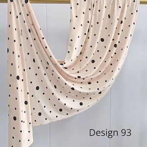 May include: A light beige fabric featuring a pattern of black polka dots of varying sizes, draped over a horizontal gold rod. The fabric hangs in soft folds, and the text Design 93 is printed in black in the lower right corner of the image.