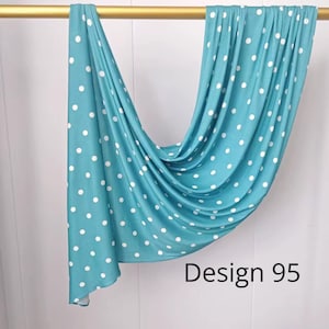 May include: A teal fabric scarf featuring a white polka dot pattern draped over a gold rod. The fabric hangs in soft folds, displaying a consistent print throughout. The text "Design 95" is printed in black in the lower right corner of the image.