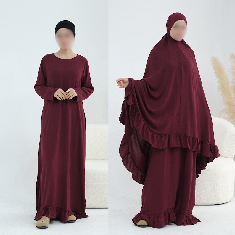 May include: A deep burgundy long-sleeved maxi dress with a ruffled hemline, paired with a matching burgundy head covering that features a ruffled edge. The outfit is shown in two views, one with a black head cap and one with the full head covering.