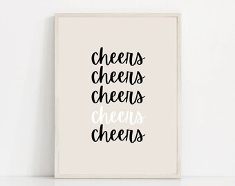 May include: A framed print with the word "cheers" repeated five times in black cursive lettering on a light beige background. The word "cheers" is in white on the fourth line.
