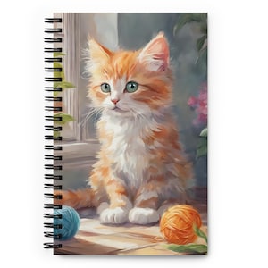 May include: Spiral-bound notebook featuring a watercolor illustration of a fluffy orange and white kitten with green eyes. The kitten sits near a window with two balls of yarn, one blue and one orange. The notebook has a black spiral binding.