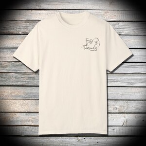 Puede incluir: Una camiseta de color crema con un diseño gráfico negro que dice "Feast of Tabernacles" con una ilustración de cabeza de león.