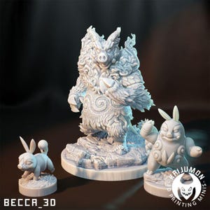Puede incluir: Tres figuras blancas impresas en 3D de criaturas fantásticas. La más grande es una figura parecida a un jabalí con detalles en forma de llama. Dos figuras más pequeñas se asemejan a conejos con rasgos de cerdo. La base de cada figura es un terreno rocoso. El texto "BECCA_3D" y "KAIJUMON MINIS" son visibles.