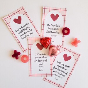 May include: Four pink and red Valentine's Day cards with bible verses about love. Each card has a red heart and a pink and red checkered background. The cards are surrounded by red and pink candy hearts.