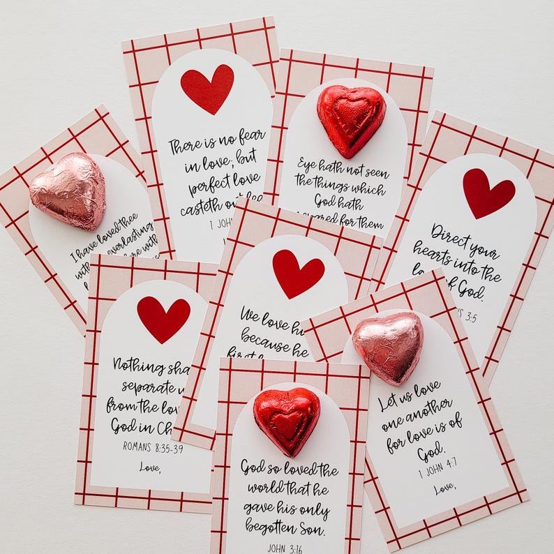 May include: A set of eight Valentine's Day cards with red and pink hearts and scripture verses about love. Each card has a small chocolate heart attached to it.
