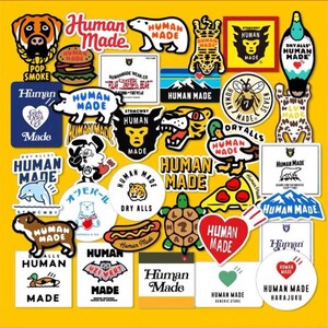 以下が含まれることがあります： 様々なデザインと「Human Made」の文字が入ったカラフルなステッカーのコレクション。動物、食べ物、ロゴの画像が黄色い背景に配置されています。 個人的なアイテムを飾るのに最適です。