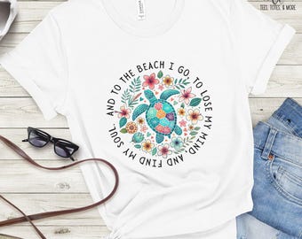 May include: White t-shirt with a vibrant turtle design encircled by flowers and the words "And to the beach I go, to lose my mind, and find my soul." The shirt is styled with blue jeans and accessories.