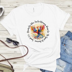 May include: White t-shirt with a colorful phoenix bird graphic and the text "Spirit of Heaviness - Isaiah 61:3 Beauty for Ashes. Joy for Mourning, Praise for The"
