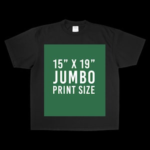 May include: A black short-sleeve t-shirt featuring a large, centered green rectangular graphic. The graphic contains white text that reads 15" X 19" JUMBO PRINT SIZE, indicating the dimensions of the available print area on the garment.