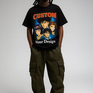 May include: A black short-sleeve t-shirt featuring a graphic print of four anime-style characters against a blue starry background. The text CUSTOM is printed in orange above the characters, and the text Your Design is printed in white below.
