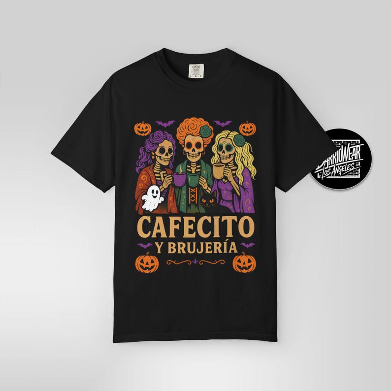 May include: Black t-shirt featuring a Halloween-themed graphic. The design includes three skeleton figures, pumpkins, bats, and the text "CAFECITO Y BRUJER&Iacute;A". A ghost and a black cat are also present in the illustration.