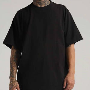 May include: A solid black t-shirt with a crew neckline and short sleeves. The garment features a plain, unpatterned design with a standard fit, providing a clean and simple look. The fabric appears opaque and consistent in colour throughout the piece.