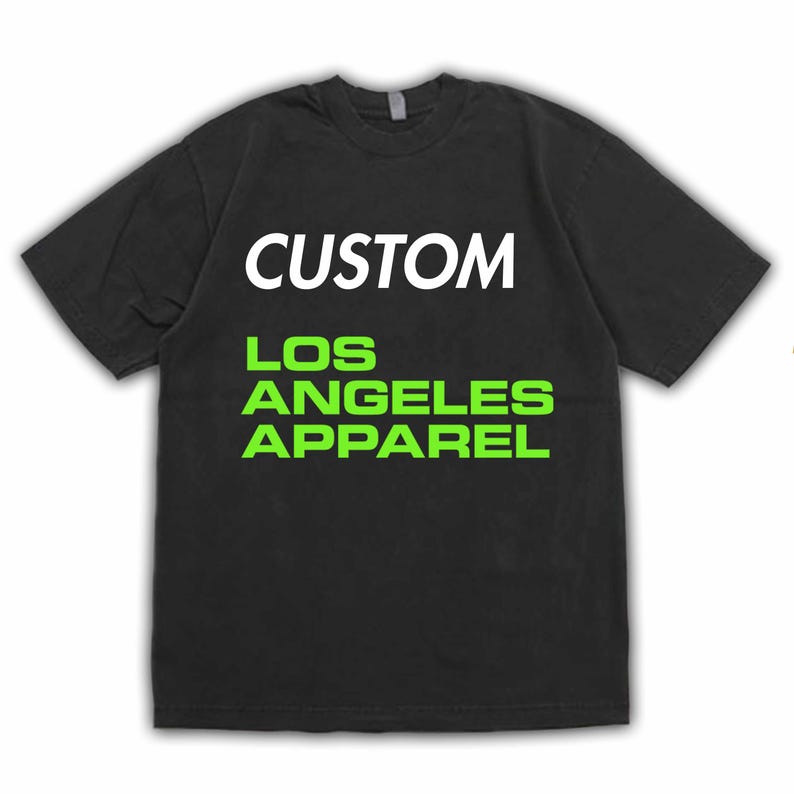 Pu&ograve; includere: T-shirt nero a maniche corte con la scritta "CUSTOM" a lettere bianche in blocco sopra "LOS ANGELES APPAREL" a lettere verdi brillanti. La maglietta &egrave; di colore uniforme e sembra essere di cotone.
