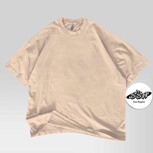 Pu&ograve; includere: Una maglietta beige oversize con scollo tondo. La maglietta &egrave; realizzata in un materiale morbido e ha maniche corte. Un logo circolare bianco con la scritta "SSA Los Angeles" si trova nell'angolo in basso a destra.