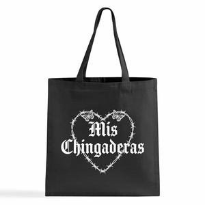 K&ouml;nnte beinhalten: Schwarze Tragetasche mit wei&szlig;em Text und einem herzf&ouml;rmigen Design. Das Herz wird von Stacheldraht gebildet und tr&auml;gt die Worte "Mis Chingaderas" in gotischer Schrift mit Schmetterlingsakzenten.