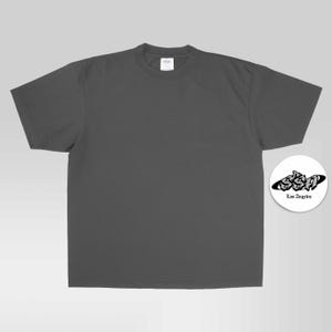 May include: A charcoal gray short-sleeve t-shirt with a crew neckline. To the right, a circular white emblem features the black text SSA in a stylized graffiti font, with the words Los Angeles printed in a smaller, simple black font underneath.