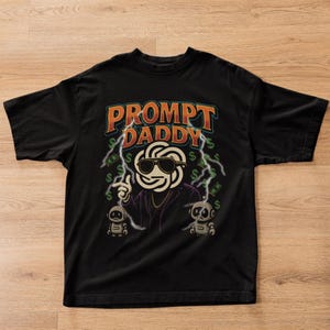 May include: Black t-shirt with the text "PROMPT DADDY" in orange and white. The graphic features a character with sunglasses, lightning bolts, dollar signs, and two small robot figures.