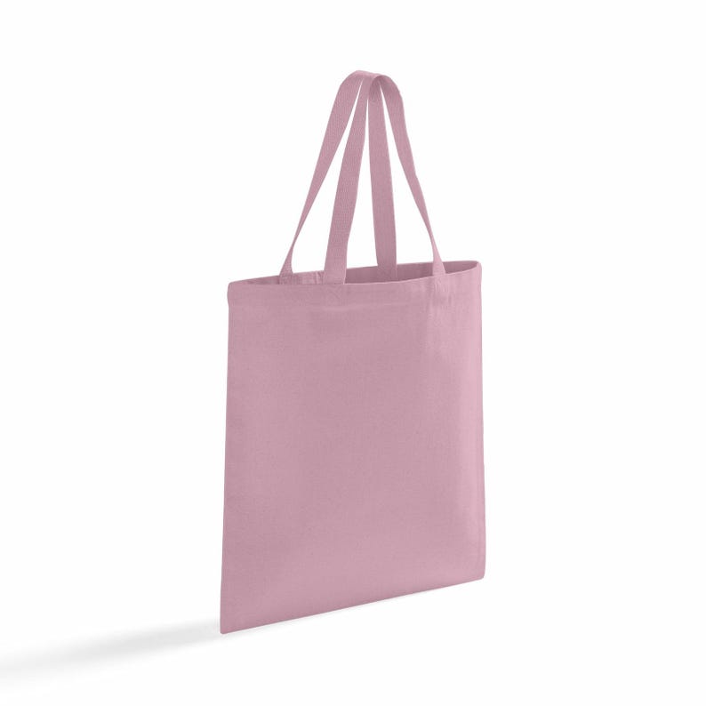 Op de afbeelding: Een lichtroze tote bag van stof. De tas heeft twee handvatten en een rechthoekige vorm. De handvatten hebben dezelfde kleur als de tas. De tas is leeg en staat rechtop tegen een witte achtergrond.