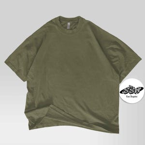 Pu&ograve; includere: T-shirt verde oliva a maniche corte, girocollo e vestibilit&agrave; ampia. Un logo bianco e nero con la scritta "Los Angeles" &egrave; in basso a destra.
