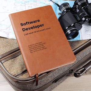Peut inclure: Un carnet relié en cuir marron avec les mots "Software Developer" gravés sur la couverture. Le carnet comprend également une définition du terme et une description du rôle.