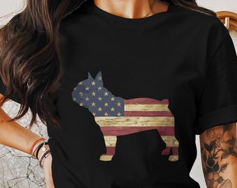 Puede incluir: Camiseta negra con la silueta de un bulldog francés con un patrón de bandera estadounidense. La bandera tiene un aspecto desgastado y una textura de madera.