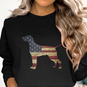 May include: Black sweatshirt with a silhouette of a dog printed on the front. The dog is outlined in the colors of the American flag.