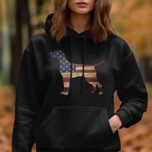 May include: Black hoodie with a silhouette of a dog printed on the front. The dog is filled with the colors of the American flag.