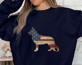 May include: A navy blue sweatshirt featuring a silhouette of a German Shepherd dog printed on the front. The dog is outlined in the colours of the American flag.
