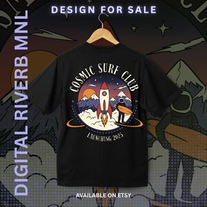 May include: Black t-shirt with a circular graphic featuring a rocket, mountains, and a surfer with a surfboard. The text "COSMIC SURF CLUB" and "LAUNCHING 2025" are displayed. The words "DESIGN FOR SALE" and "DIGITAL RIVERB MNL" are also visible.
