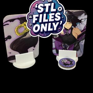 May include: Two printed cards with anime-style illustrations, held by white stands. One card features a character with purple accents, the other a gold rope. A small circular token rests in front. The text "STL FILES ONLY" is displayed above.