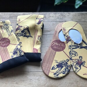 May include: A pair of yellow and brown socks with a graphic print of athletes running. The socks have the text "Pee Chee Art Studio Portfolio" on them.
