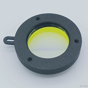 May include: A black plastic ring with a yellow inner ring and a clear window. The ring has a small handle on the side.