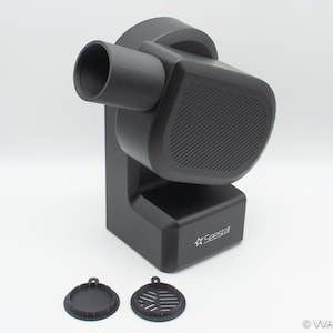 May include: Black plastic fan with a round, textured speaker grill and a nozzle on the side. The fan has a white logo that says "Seestar" on the front. Two black plastic filters are in the foreground.