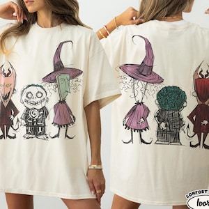 May include: An ivory t-shirt featuring a graphic print of three characters from The Nightmare Before Christmas. The front shows the characters facing forward, while the back displays the same characters from behind. The text Comfort Colors Ivory is visible.