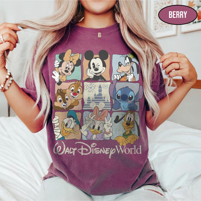 May include: A berry-colored short-sleeve t-shirt featuring a grid of nine squares with illustrations of Disney characters including Mickey Mouse, Minnie Mouse, Goofy, Donald Duck, Daisy Duck, Pluto, Chip, Dale, and Stitch, with the text Walt Disney World.