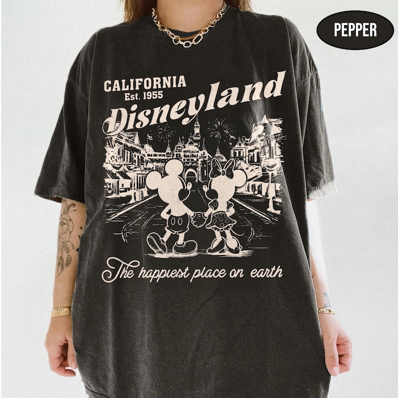 May include: Dark gray t-shirt with a Disneyland graphic. The design features Mickey and Minnie Mouse, the text "California Disneyland Est. 1955", and "The happiest place on earth". The shirt has a vintage, distressed look.