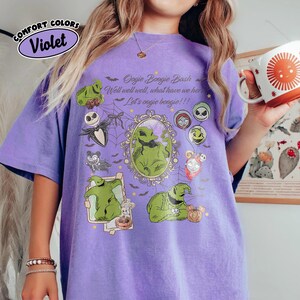 May include: Violet Comfort Colors t-shirt featuring Oogie Boogie Bash graphics. The design includes images of Oogie Boogie, Jack Skellington, and other characters from The Nightmare Before Christmas, with text that reads "Oogie Boogie Bash".