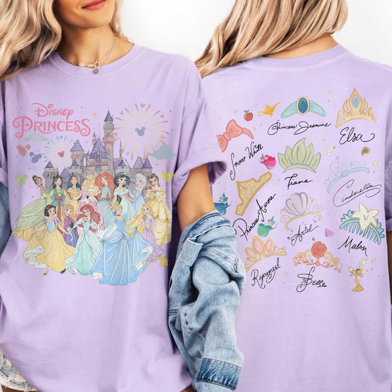 K&ouml;nnte beinhalten: Ein hellviolettes T-Shirt mit einer Grafik von Disney-Prinzessinnen vor einem Schloss auf der Vorderseite und einer Sammlung von Prinzessinnennamen, Kronen und Symbolen auf der R&uuml;ckseite. Das T-Shirt ist von vorne und hinten zu sehen.