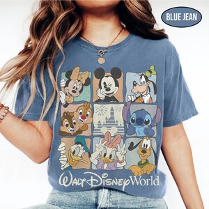 May include: A blue jean colored t-shirt featuring a grid of nine squares displaying various Disney characters including Mickey Mouse, Minnie Mouse, Goofy, Donald Duck, Daisy Duck, Pluto, Chip, Dale, and Stitch, with the text Walt Disney World.