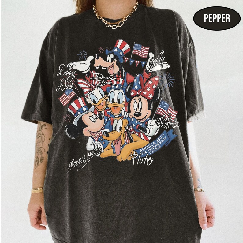 Może przedstawiać: Czarny t-shirt z kolorową grafiką postaci Disneya, w tym Myszki Miki i Myszki Minnie, Kaczora Donalda i Kaczki Daisy, Goofy'ego i Pluto, z amerykańskimi flagami. Koszulka upamiętnia 250. rocznicę USA.