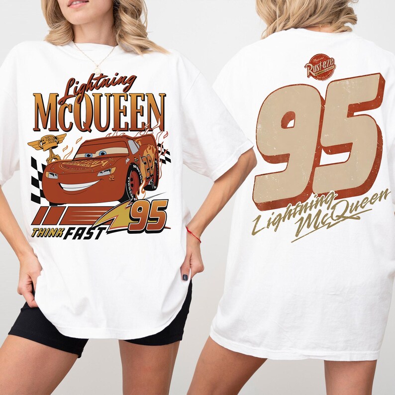May include: White t-shirt with a Lightning McQueen design. The front shows the character, the text "Lightning McQueen", and "95". The back has a large "95" and "Lightning McQueen" text. A fun, casual tee.