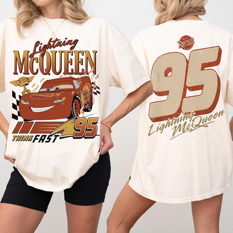 May include: Cream-coloured t-shirt featuring Lightning McQueen from the Cars film. The front graphic includes the character's image, the text "Lightning McQueen," and the number "95." The back displays a large "95" and "Lightning McQueen" text.