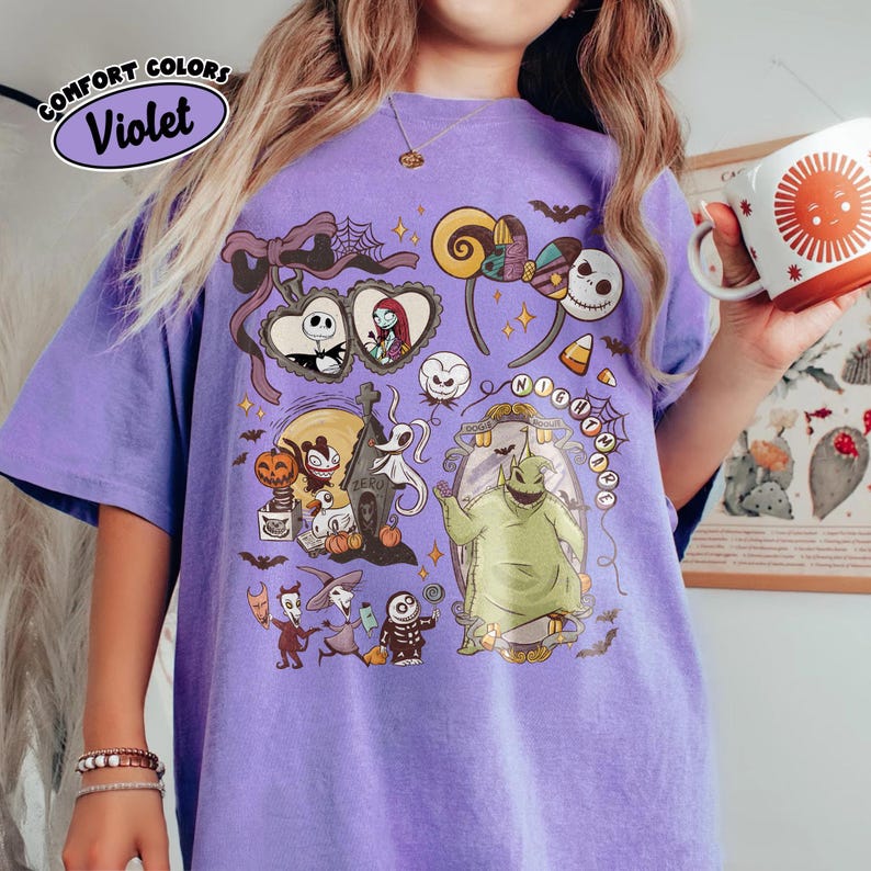 May include: A violet Comfort Colors t-shirt featuring a colorful graphic of characters from The Nightmare Before Christmas. The design includes Jack Skellington, Sally, Oogie Boogie, and other elements from the movie. The shirt has a relaxed fit.
