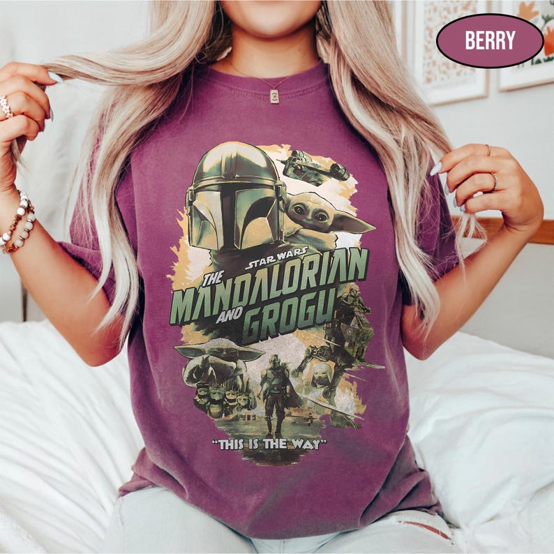 May include: Berry-colored t-shirt featuring a graphic from Star Wars: The Mandalorian. The design includes the Mandalorian helmet, Grogu, and the text "The Mandalorian and Grogu" and "This is the Way."