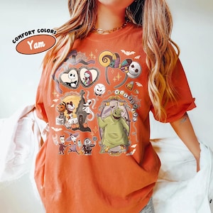 May include: Orange Comfort Colors t-shirt featuring a variety of cartoon characters and imagery from The Nightmare Before Christmas. The shirt includes the text "Comfort Colors" and "Yam" in an oval. The shirt has short sleeves.